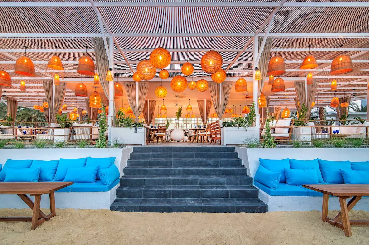 Terrasse des Radisson Blu Hotel & Resort in Abu Dhabi Corniche mit orangefarbenen Lampen und blauen Kissen