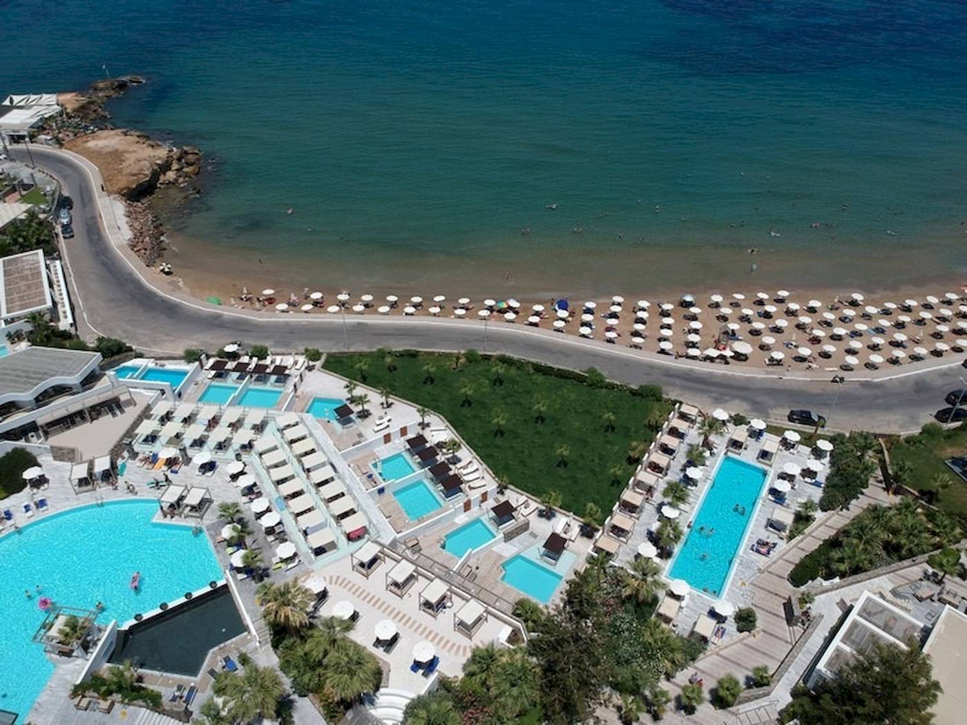 Oberflächenansicht des The Island Hotel auf Kreta mit mehreren Swimmingpools, Liegen und Sonnenschirmen.