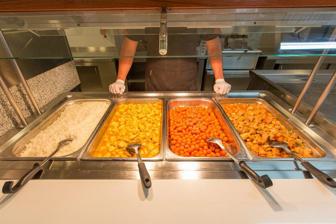 Buffettisch mit Reis, Curry und Gemüse, ein Mitarbeiter im Hintergrund.