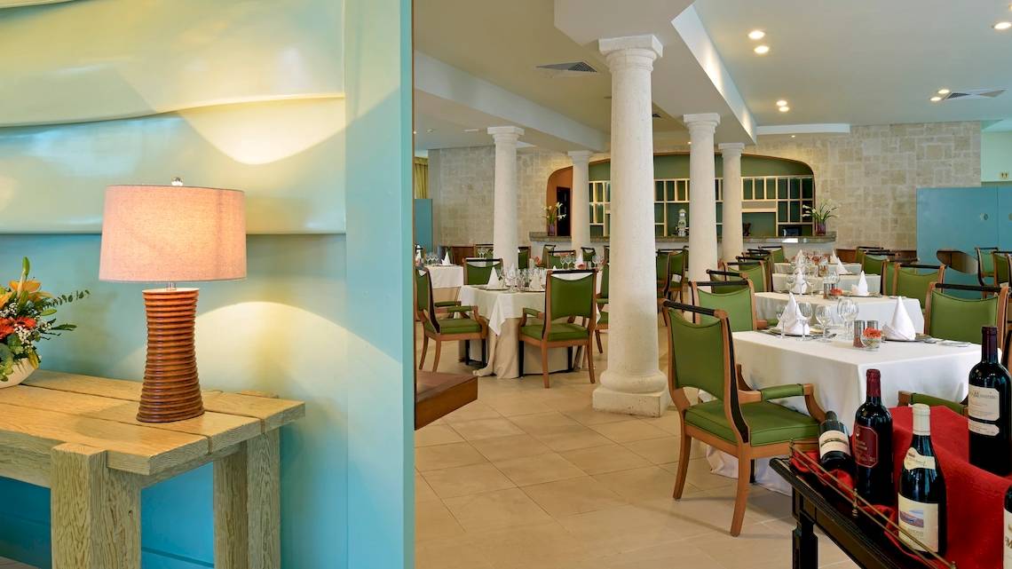 Restaurant Ambiente im JOIA Bávaro by Iberostar Hotel mit Tisch, Stühlen und Flaschen.