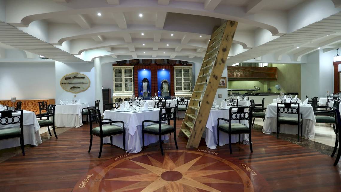 Innenansicht des Restaurants im JOIA Bávaro Hotel mit gedeckten Tischen und einer Leiter.