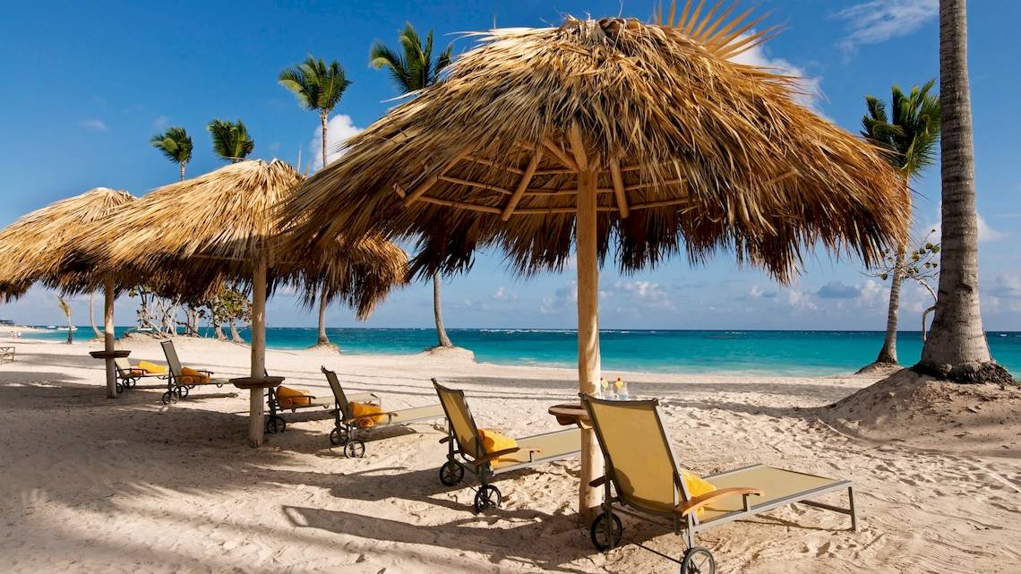 Strand mit Sonnenliegen und Strohschirmen im JOIA Bávaro by Iberostar Hotel