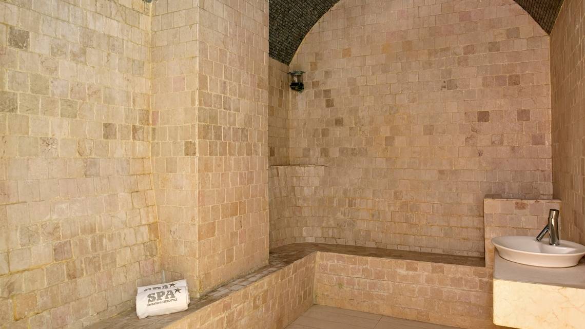 Sauna im JOIA Bávaro by Iberostar Hotel mit Steinwänden und Sitzbank.