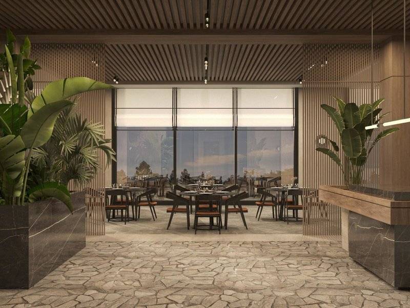 Innenansicht des Restaurants im Jaz Elite Amara Hotel mit Tischen, Stühlen und Pflanzen.
