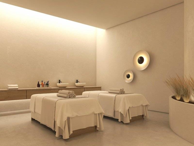 Spa-Behandlungsraum im Jaz Elite Amara Hotel mit zwei Behandlungstischen, weißen Wänden und Deckenbeleuchtung.