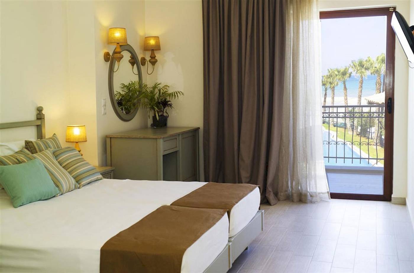 Doppelzimmer im Almyrida Beach Hotel mit Blick auf den Pool und die Palmen.