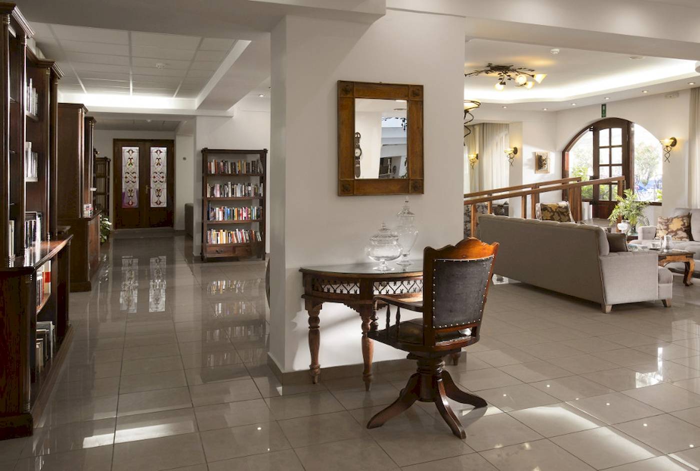 Empfangsbereich des Almyrida Beach Hotels mit gefliestem Boden, Couch, Tisch und Bücherregal.