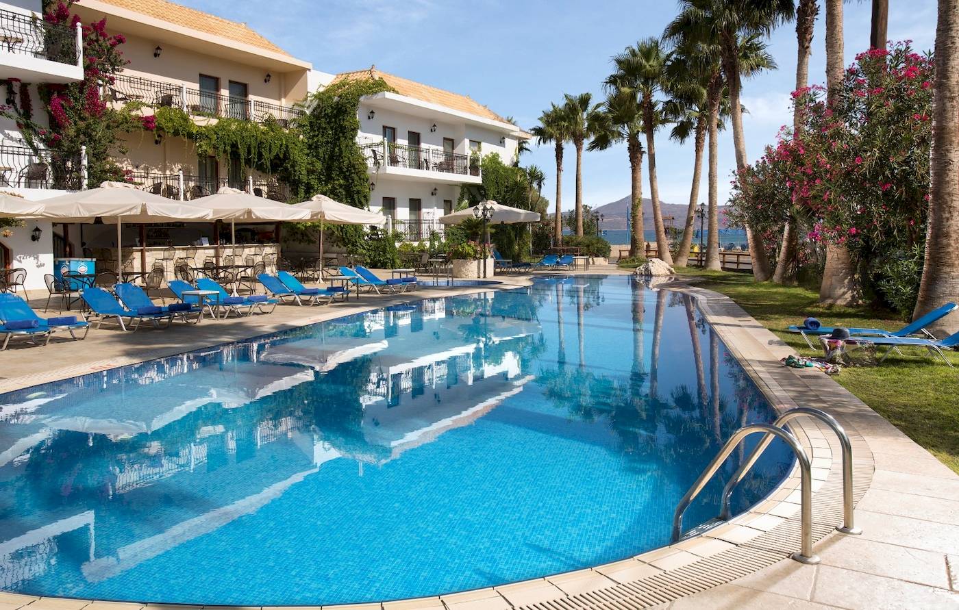 Außenbereich des Almyrida Beach Hotel mit Pool und Liegestühlen.