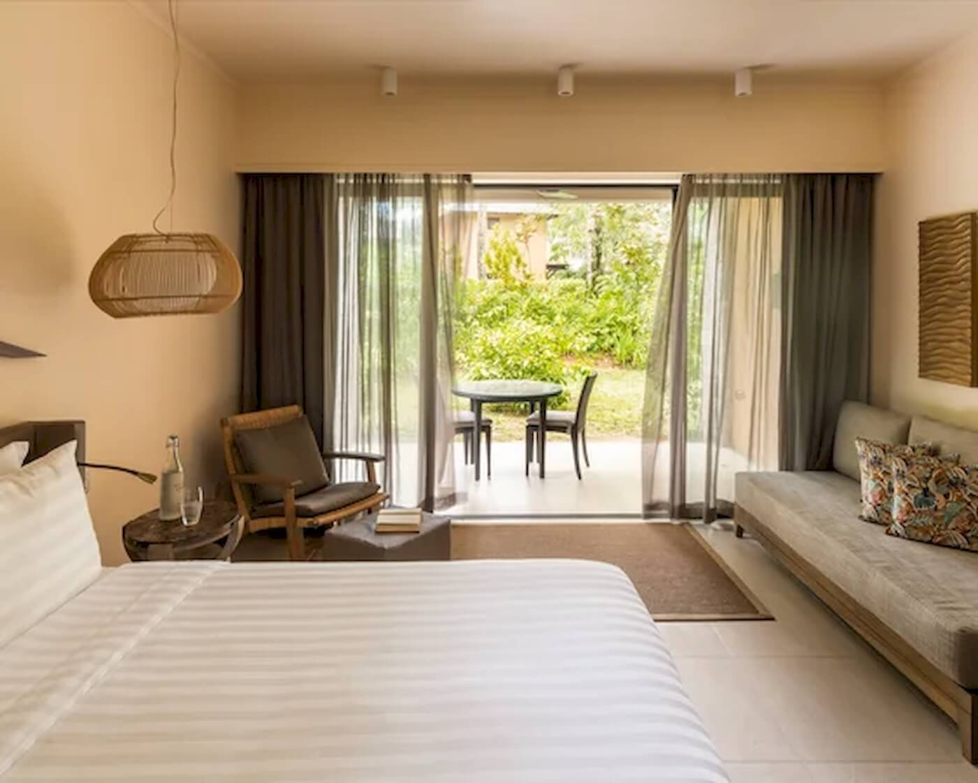 Schlafzimmer im Constance Ephelia Resort mit Blick auf den Garten und einem Tisch mit Stühlen.