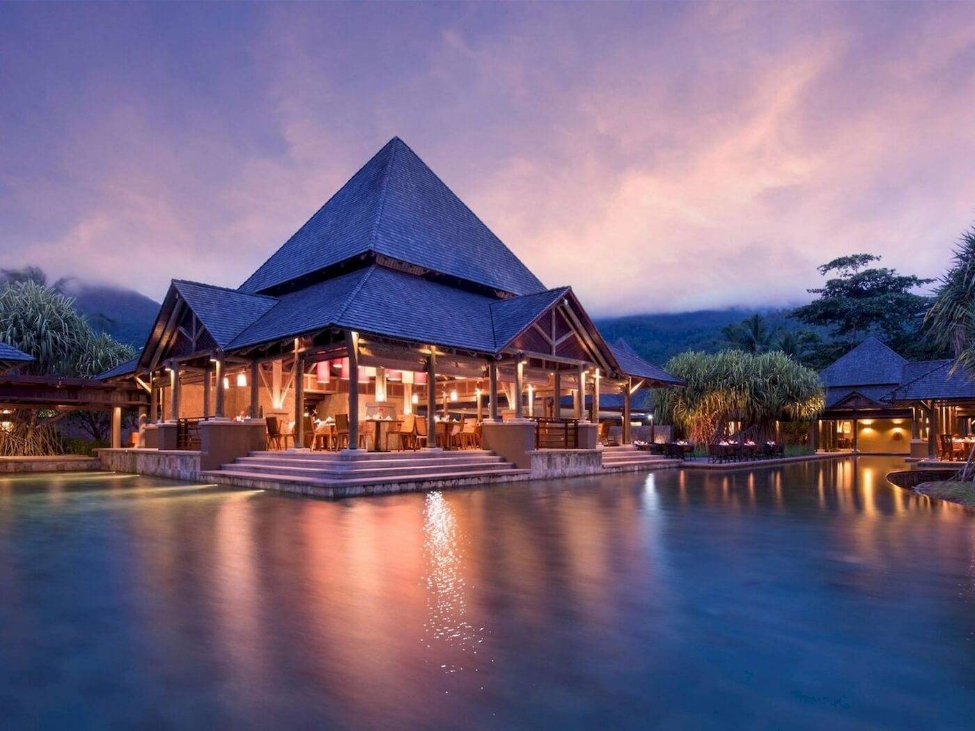 Nachtansicht des Constance Ephelia Resorts mit blauem Dach und Pool