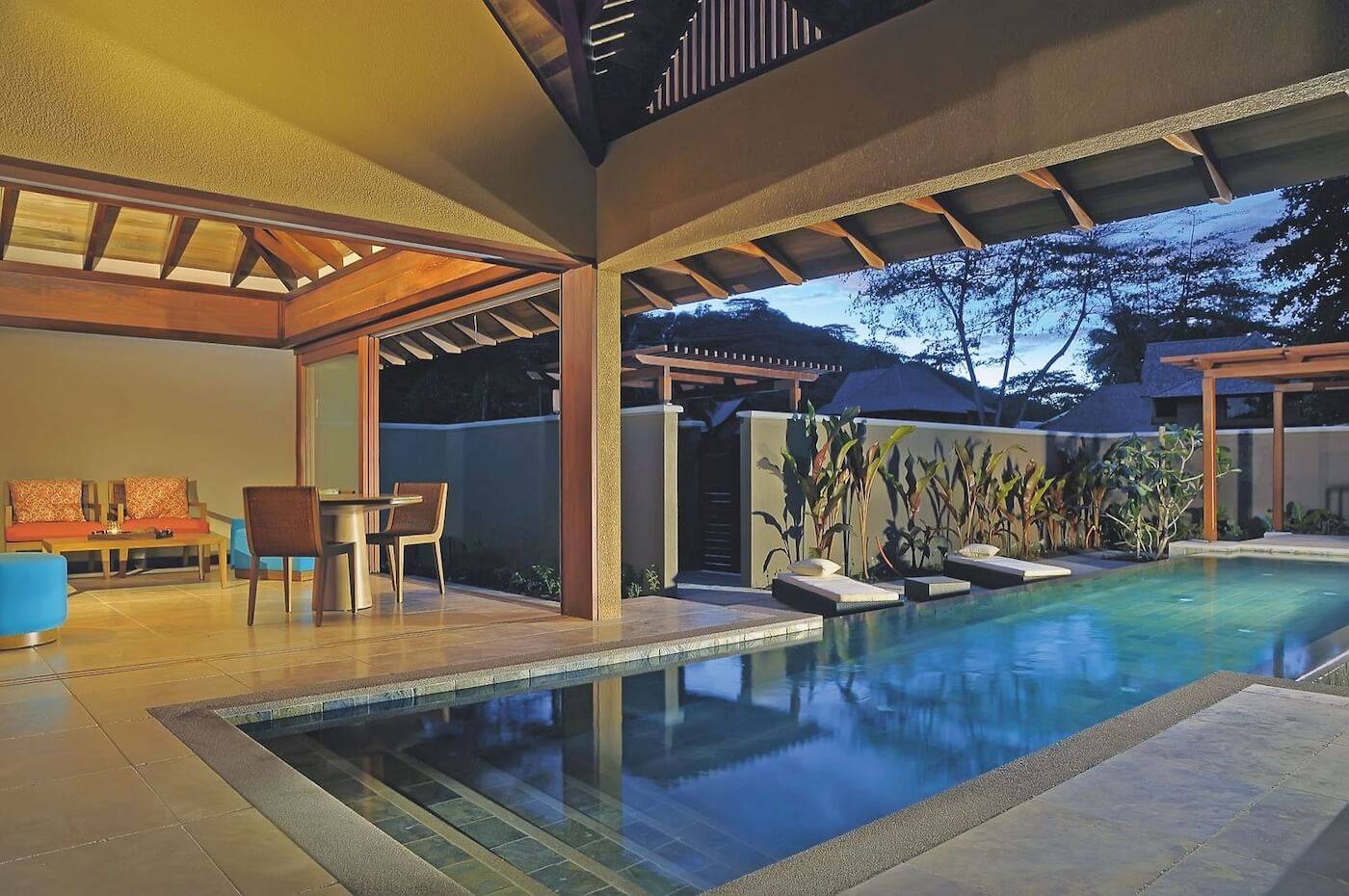 Pool-Bereich im Constance Ephelia Resort mit Sitzmöbeln und Sonnenliegen.