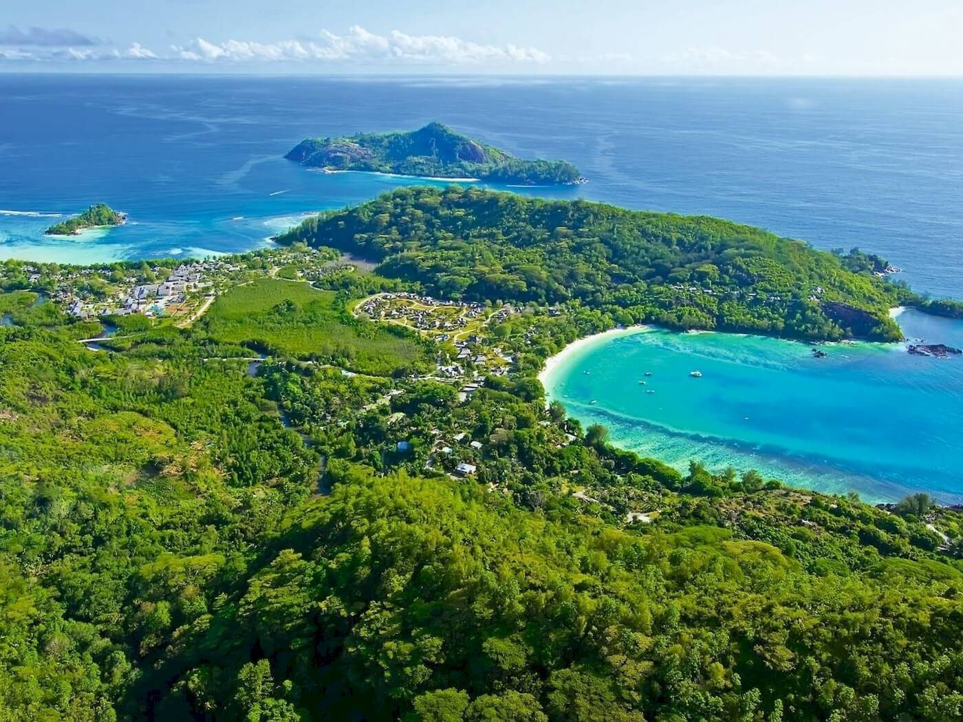 Luftaufnahme des Constance Ephelia Resorts auf einer Insel mit türkisfarbenem Wasser und grüner Vegetation.