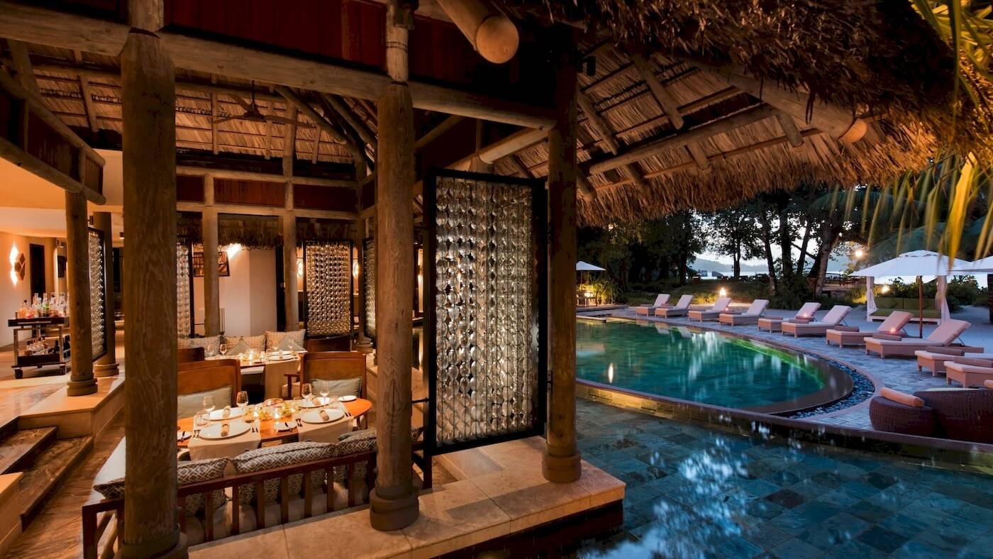 Außenbereich des Constance Ephelia Resorts mit Swimmingpool, Sonnenliegen und Pavillon.