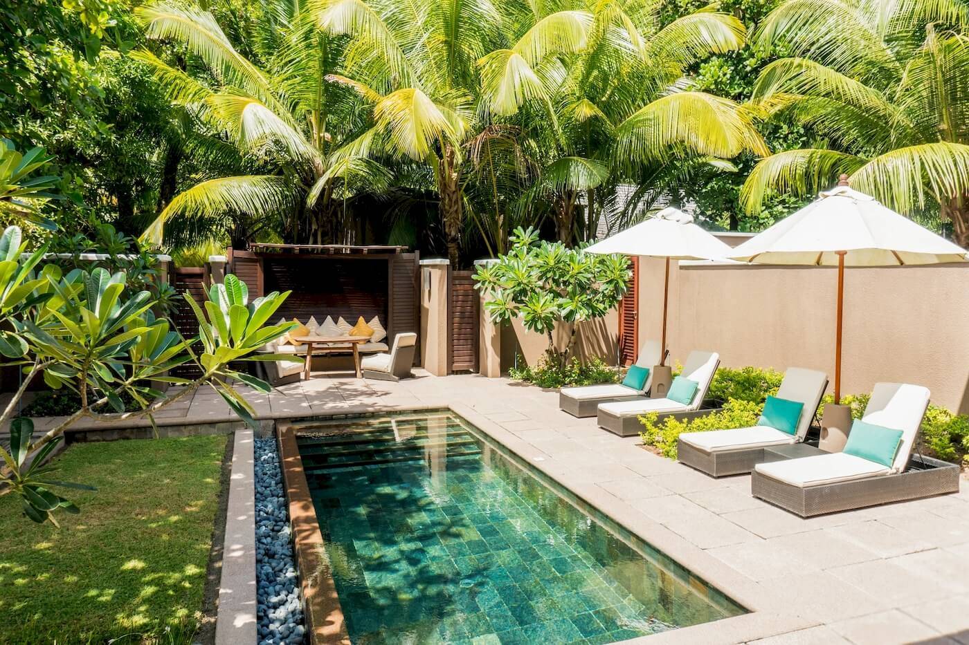 Außenbereich des Constance Ephelia Resorts mit Pool, Liegestühlen und Sonnenschirmen.