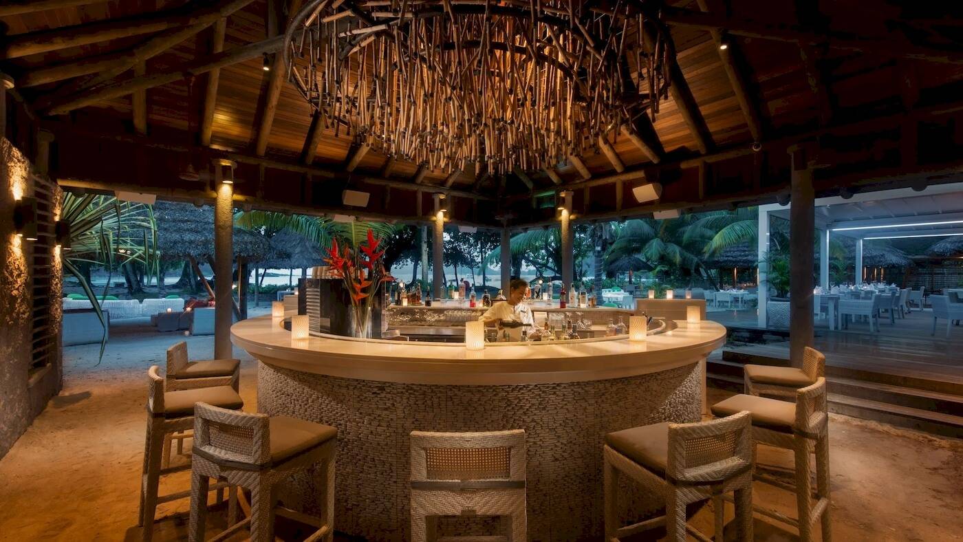 Cocktailbar im Constance Ephelia Resort mit Blick auf den Strand und Palmen.