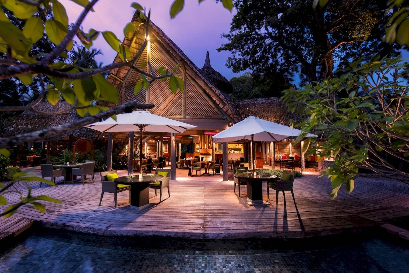 Terrasse des Constance Ephelia Resorts bei Nacht mit beleuchteten Tischen und Stühlen.