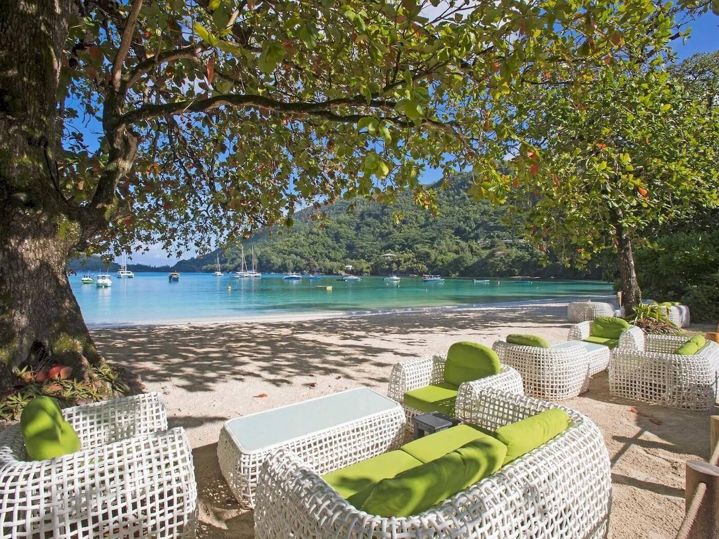 Lounge-Set am Strand des Constance Ephelia Resorts mit Blick auf das Meer und Berge.
