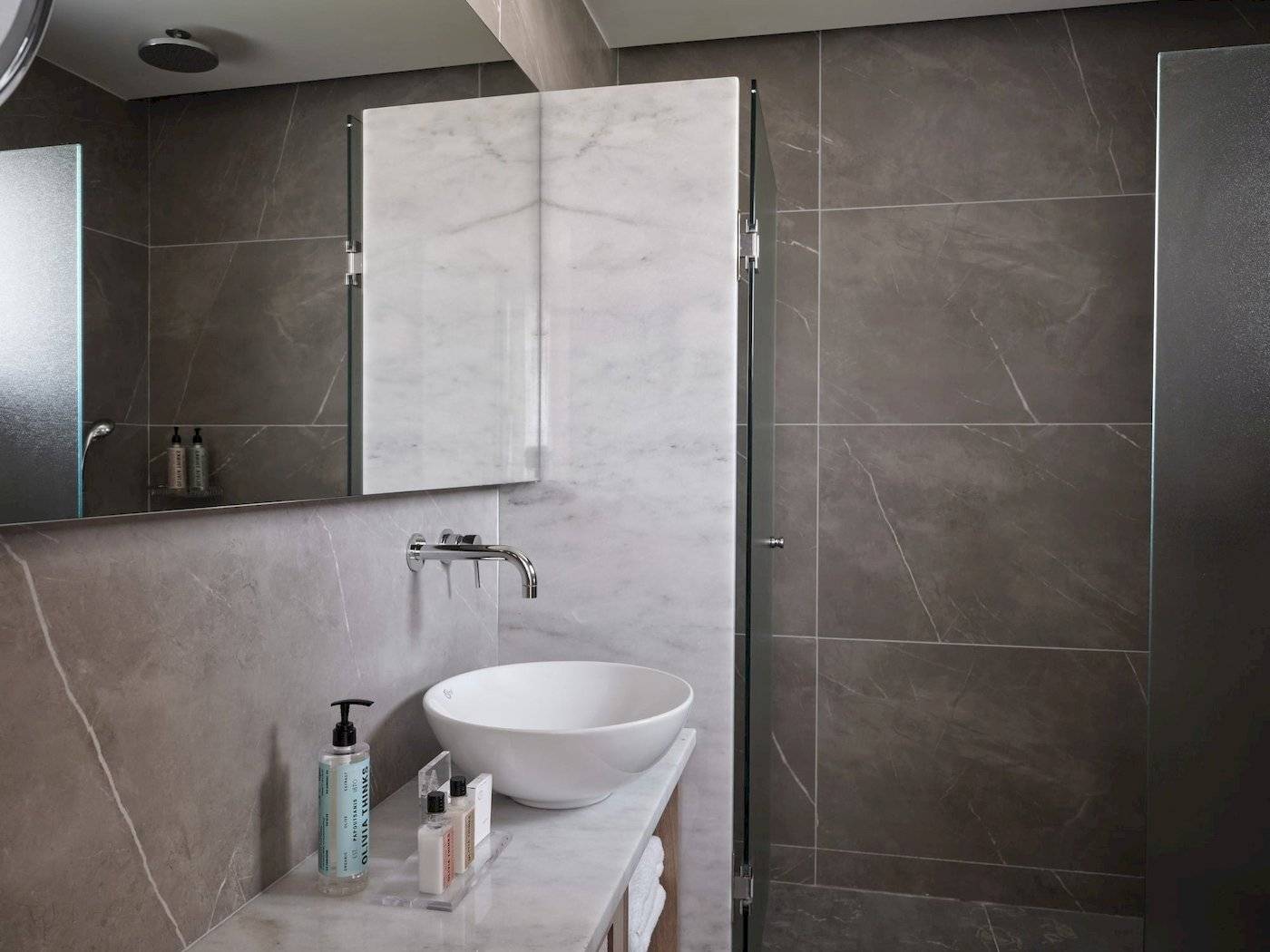 Badezimmer im Atlantica Beach Resort Kos mit grauen und weißen Fliesen und einem weißen Waschbecken.