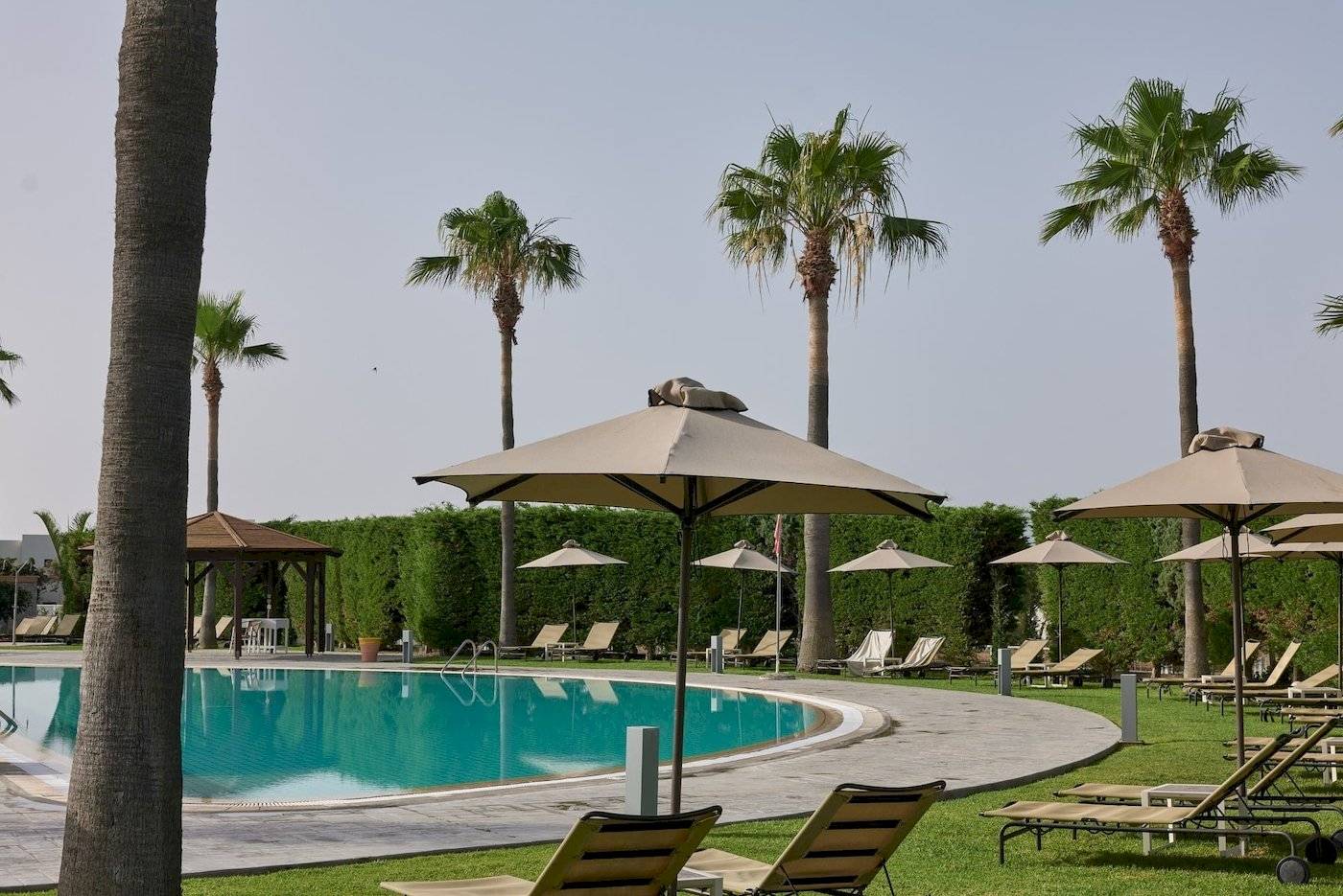 Poolbereich des Atlantica Beach Resort Kos mit Sonnenliegen und Sonnenschirmen.