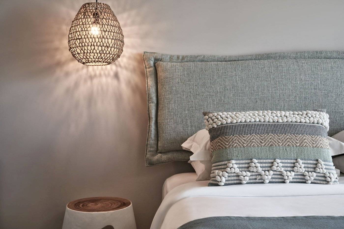 Bett im Atlantica Beach Resort Kos mit Kissen und Lampenschirm.