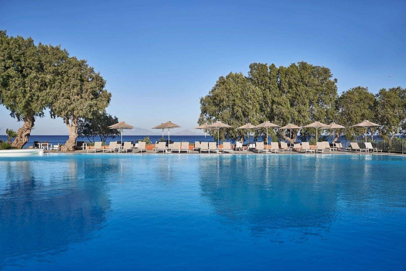 Pool mit Liegestühlen und Sonnenschirmen im Atlantica Beach Resort Kos