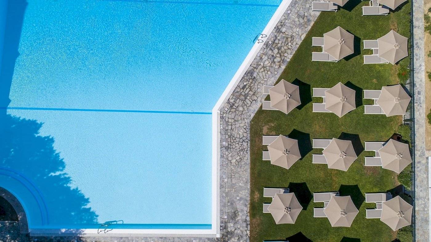 Hotelpool mit Liegestühlen und Sonnenschirmen aus der Luft
