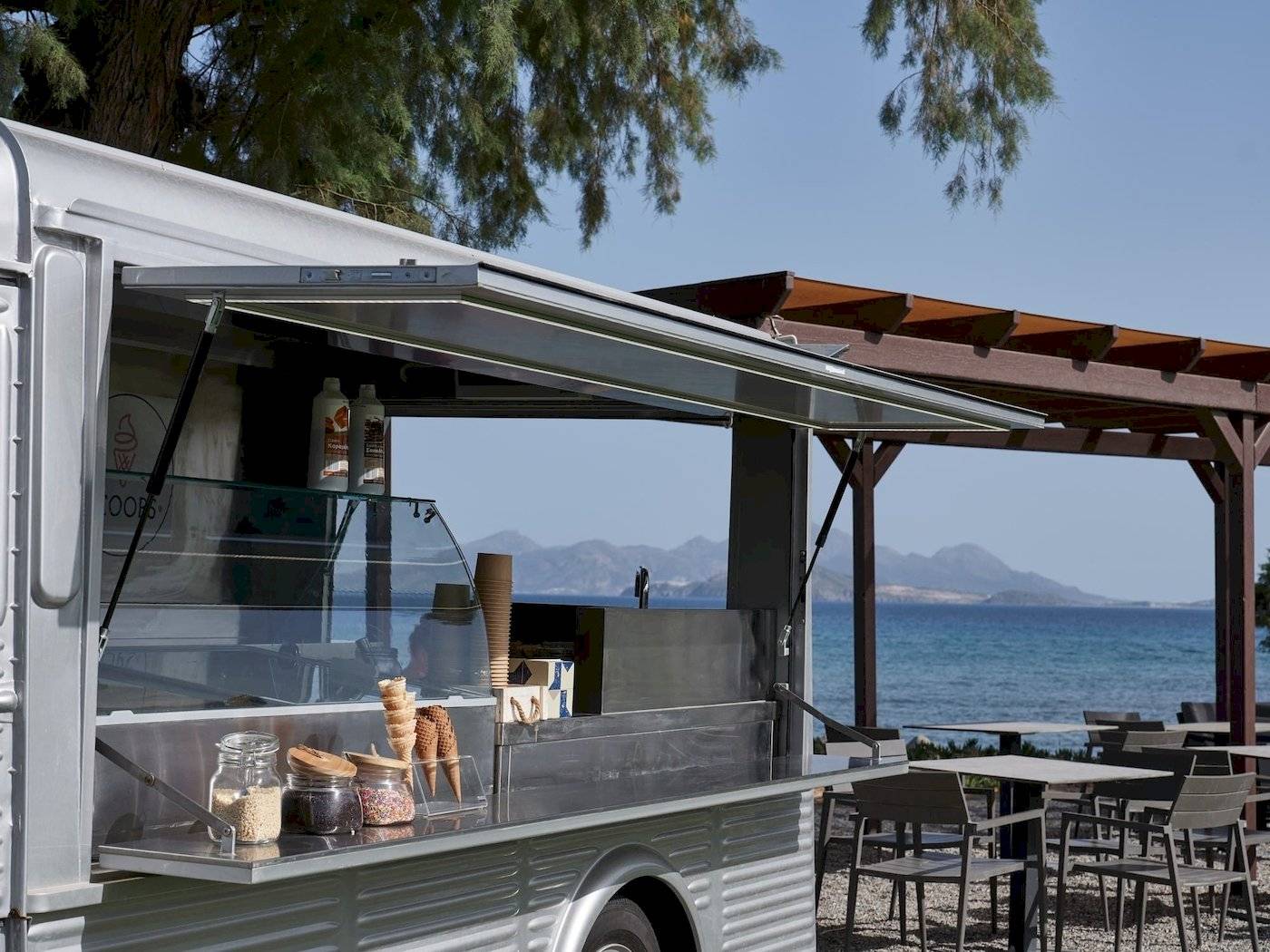 Eis-Mobil am Strand vor dem Atlantica Beach Resort Kos mit Eisbechern und Tisch.