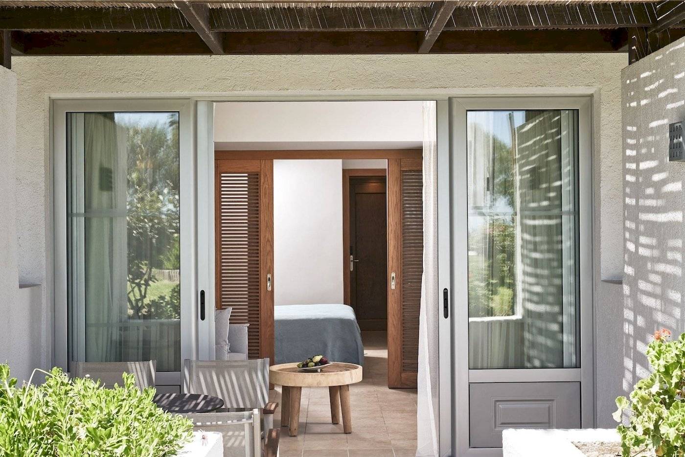 Zimmereingang des Atlantica Beach Resort Kos mit offenem Eingang, Tisch und Pflanzen.