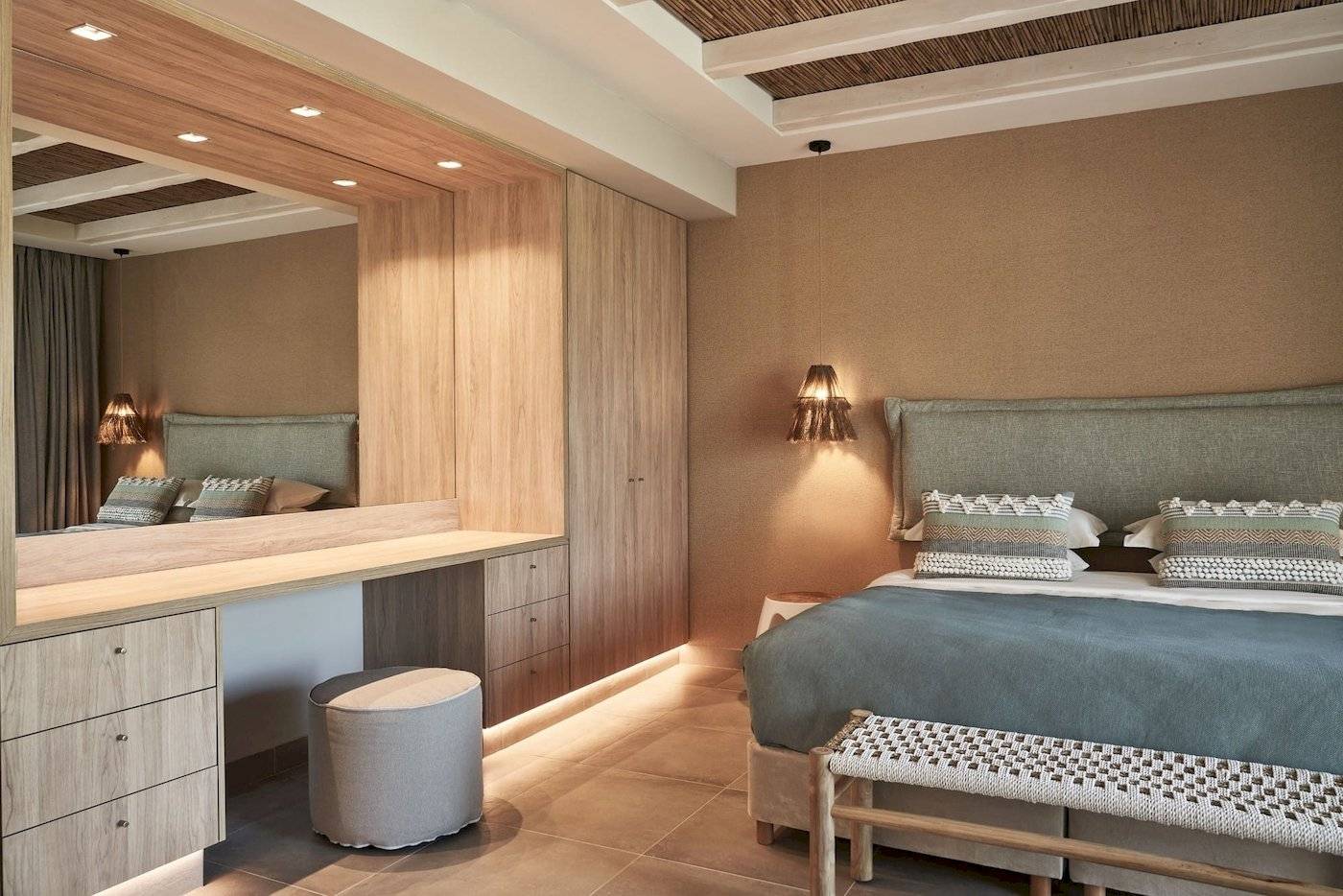 Schlafzimmer im Atlantica Beach Resort Kos mit großem Bett, Nachttischen, Spiegel und Holzmöbeln.