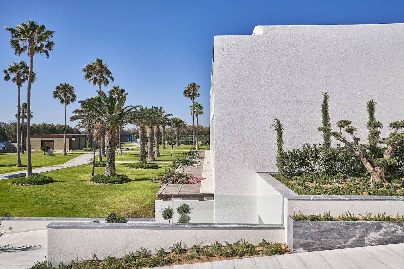 Außenbereich des Atlantica Beach Resort Kos mit weißen Gebäuden und Palmen