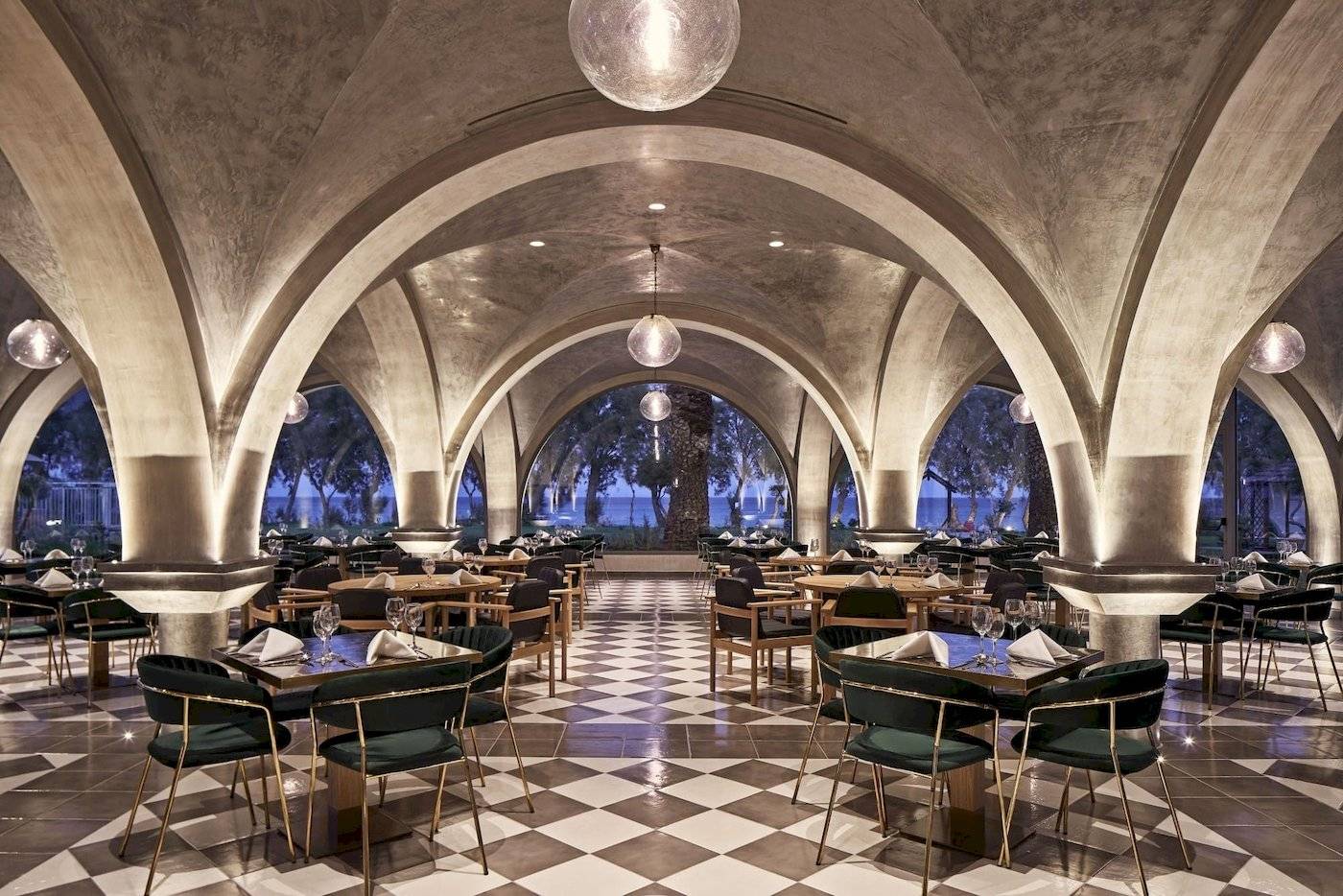 Restaurant-Innenansicht des Atlantica Beach Resort Kos mit bogenförmigen Decken und schachbrettartigem Boden.