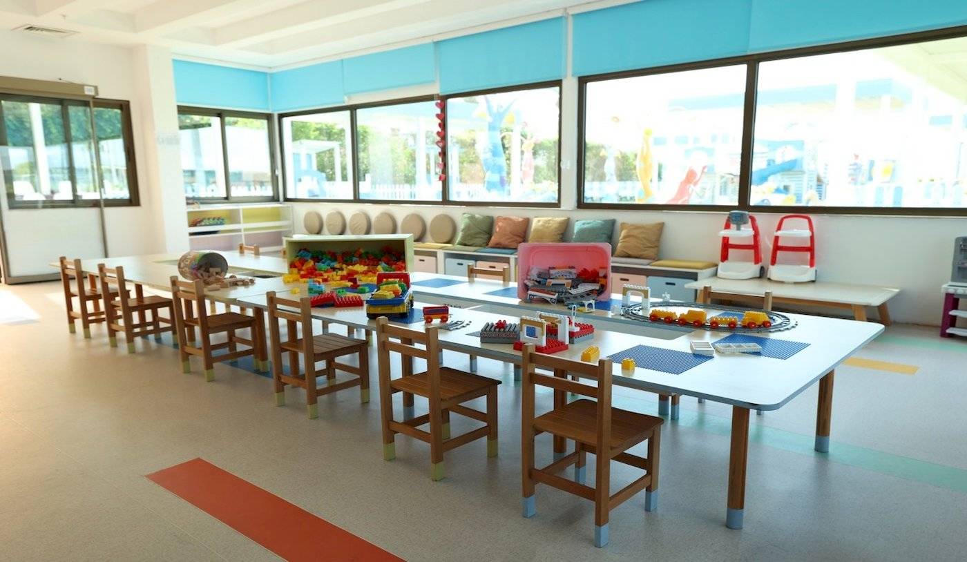Foto des Kinderspielbereichs im Nirvana Cosmopolitan Hotel mit Tischen, Stühlen und Spielzeug.