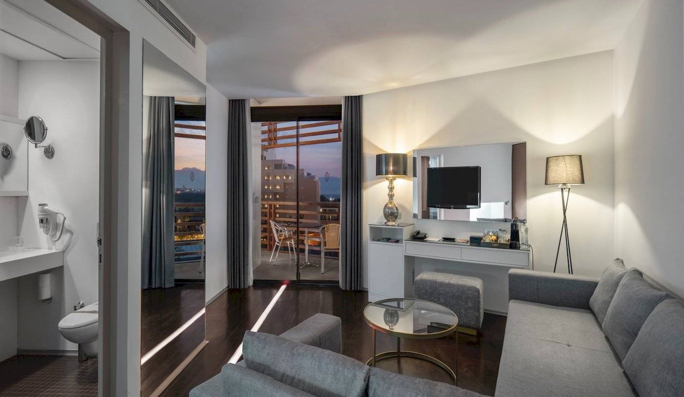 Hotelzimmer im Nirvana Cosmopolitan mit Balkon, Fernseher, Couch und Schreibtisch.