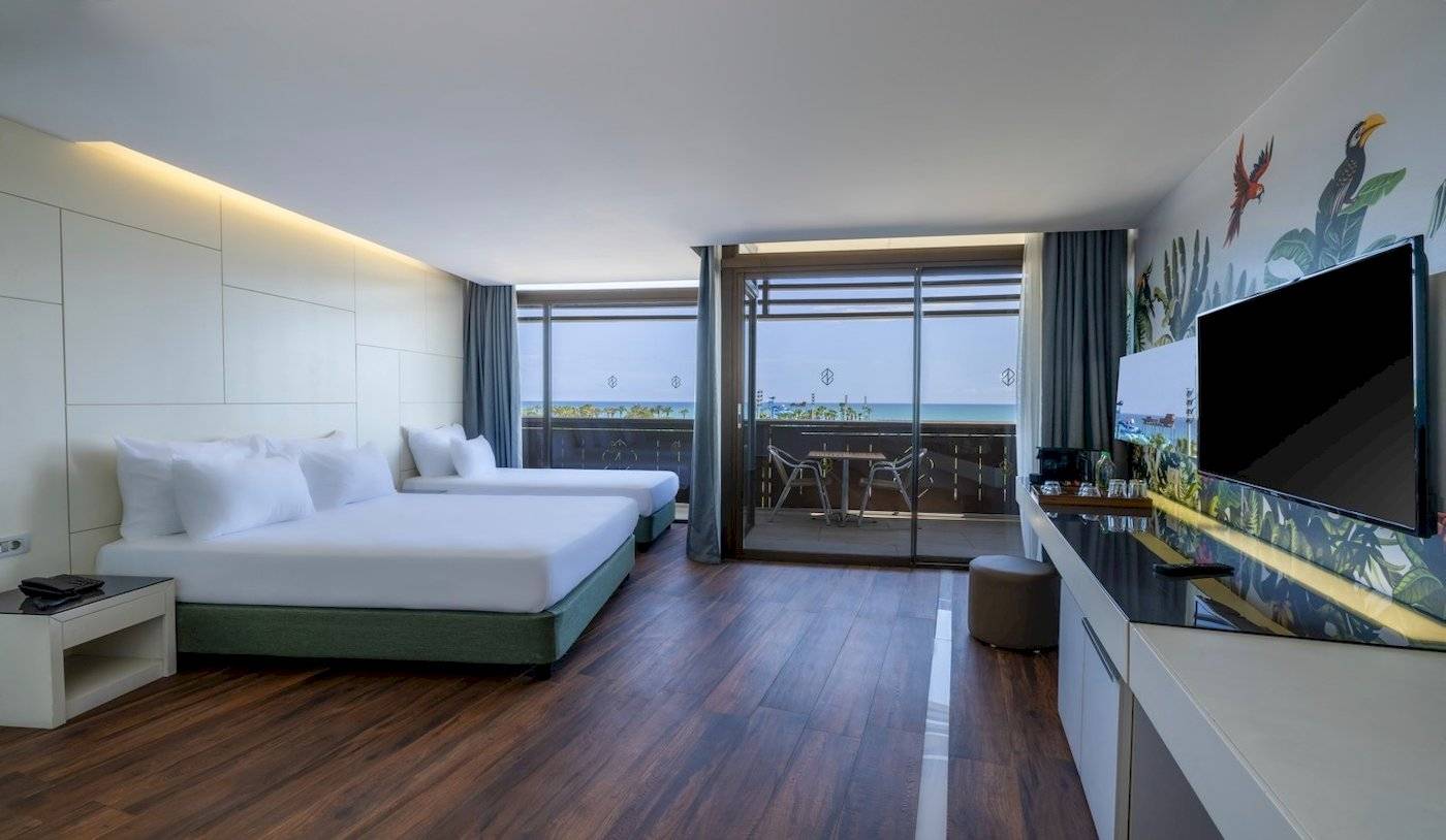 Innenansicht eines Hotelzimmers im Nirvana Cosmopolitan mit zwei Betten und Meerblick.