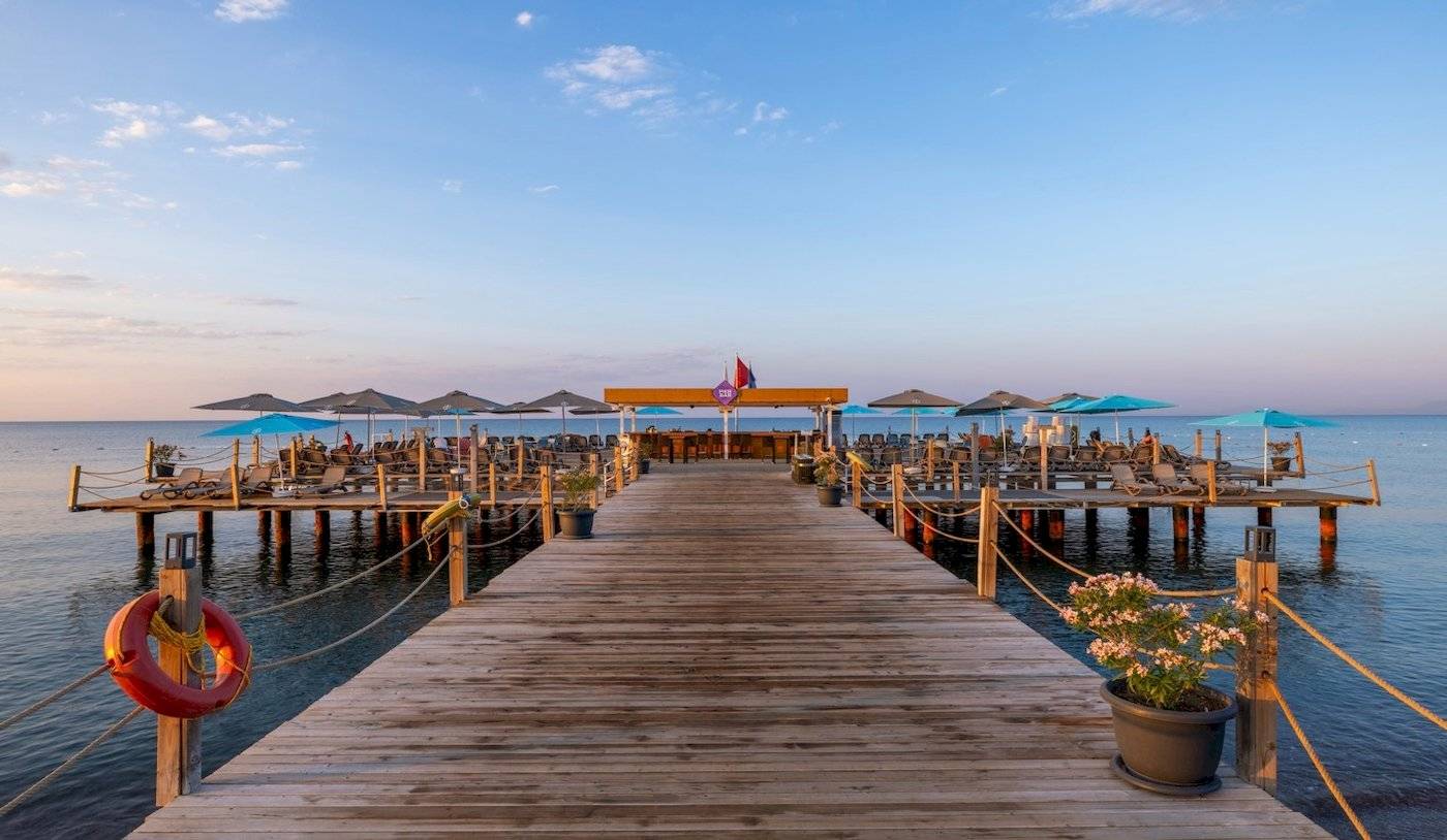 Die Terrasse des Nirvana Cosmopolitan Hotels mit Lounge-Stühlen und Sonnenschirmen am Meer.