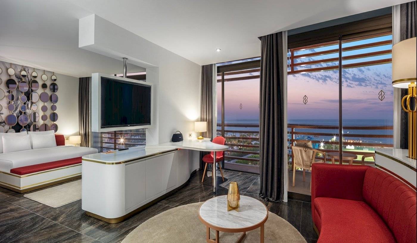 Innenansicht des Nirvana Cosmopolitan Hotels mit Bett, Schreibtisch und Aussicht auf den Ozean.