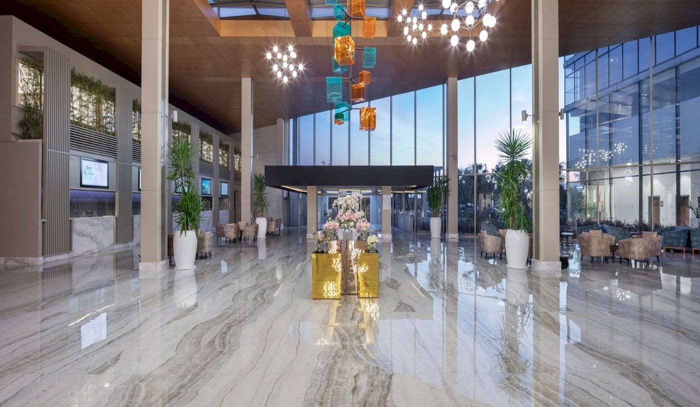 Empfangsbereich des Nirvana Cosmopolitan Hotels mit Marmorboden, großen Fenstern und modernen Möbeln.