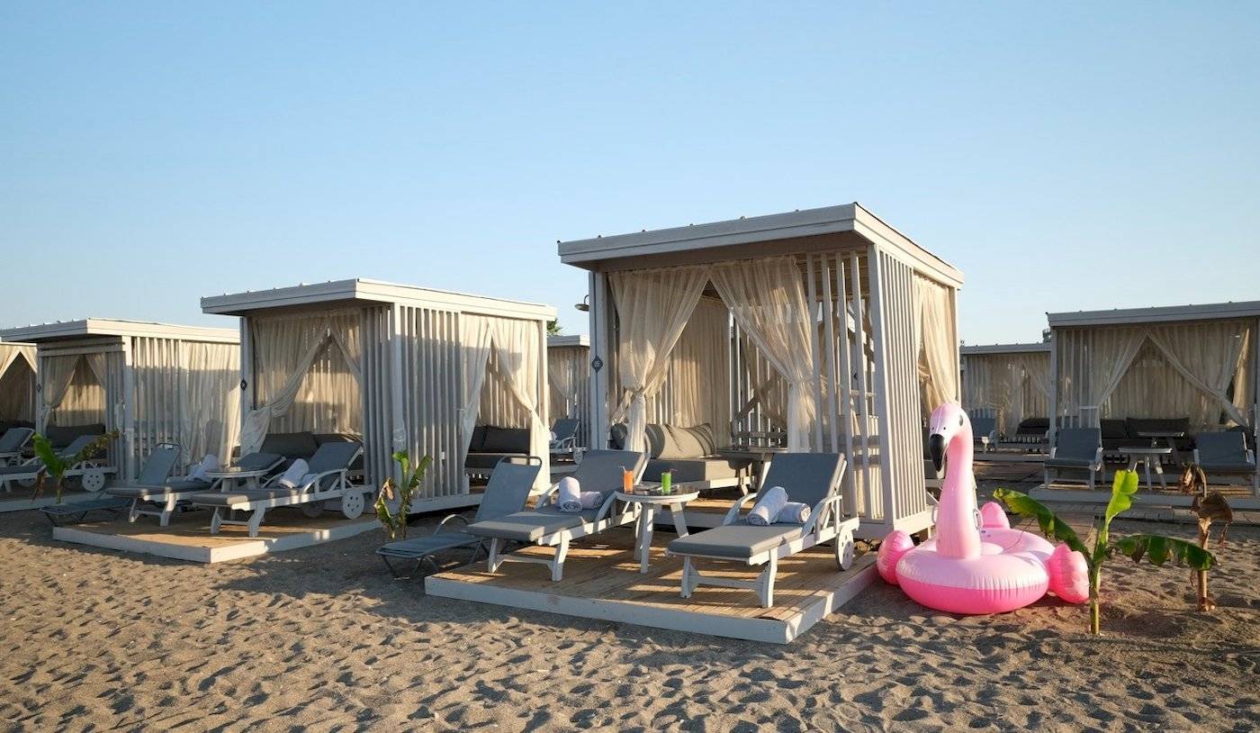 Lounges am Strand des Nirvana Cosmopolitan Hotels mit Flamingo-Pool und Sonnenliegen