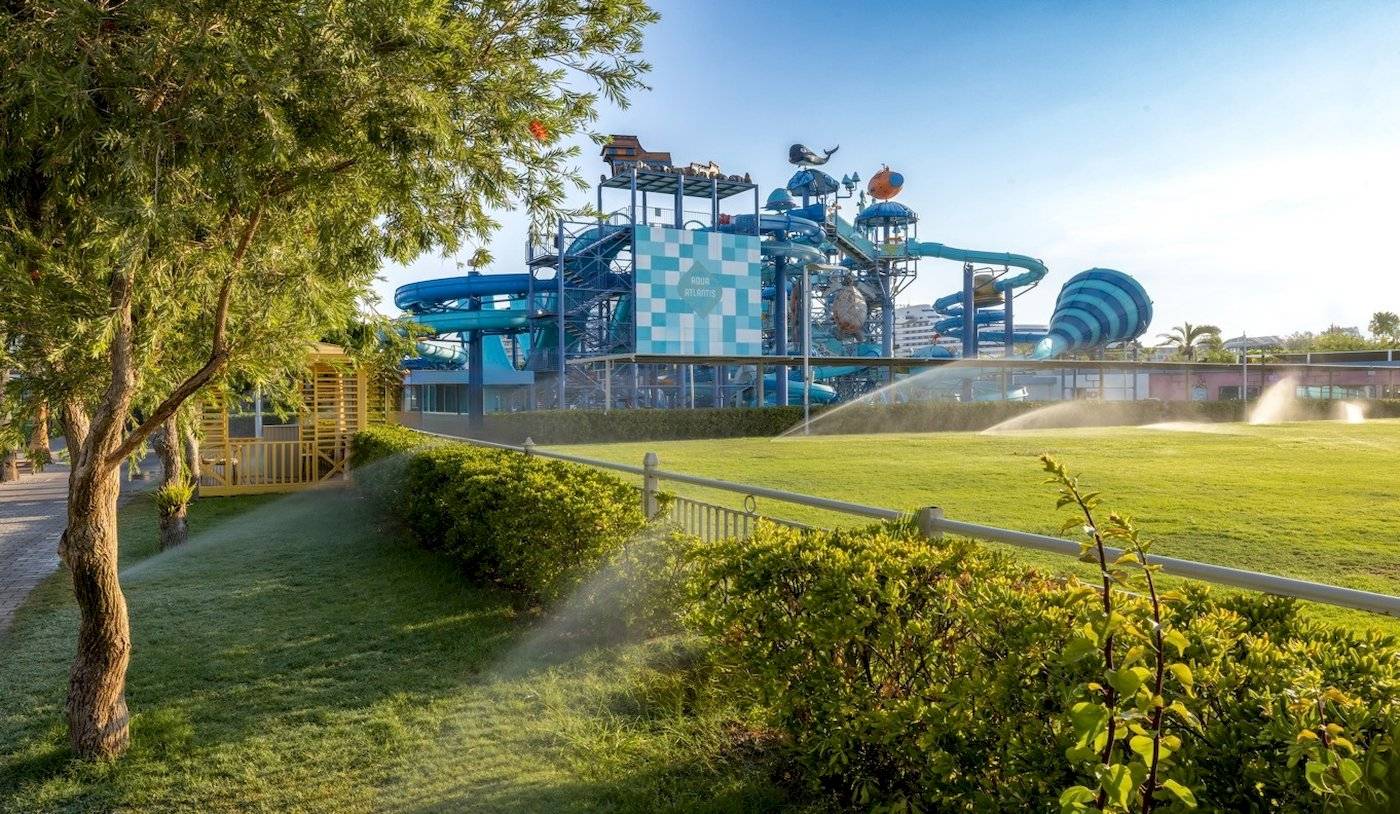 Wasserpark des Nirvana Cosmopolitan Hotels mit großen Wasserrutschen und grüner Rasenfläche.