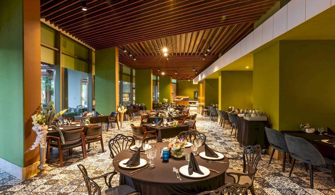 Innenraum des Nirvana Cosmopolitan Hotels mit vielen gedeckten Tischen und Stühlen.