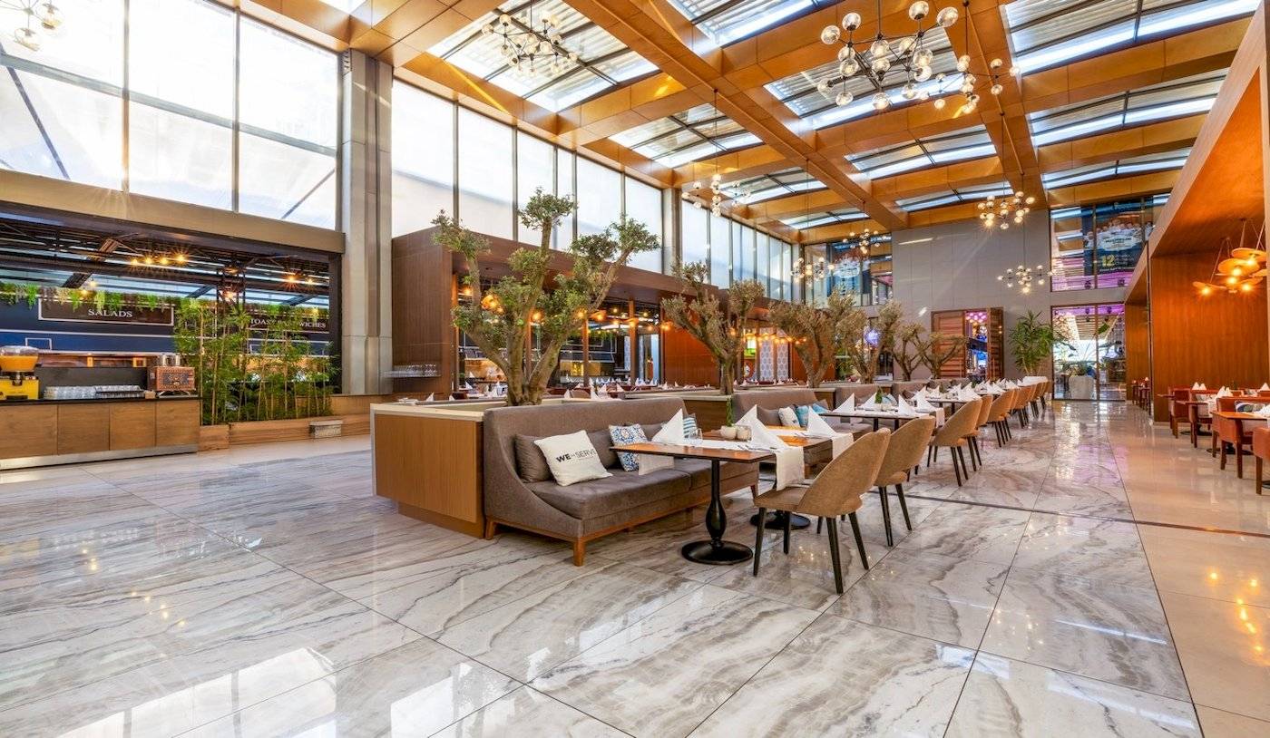 Innenbereich des Nirvana Cosmopolitan Hotels mit gepolsterten Bänken und runden Tischen.