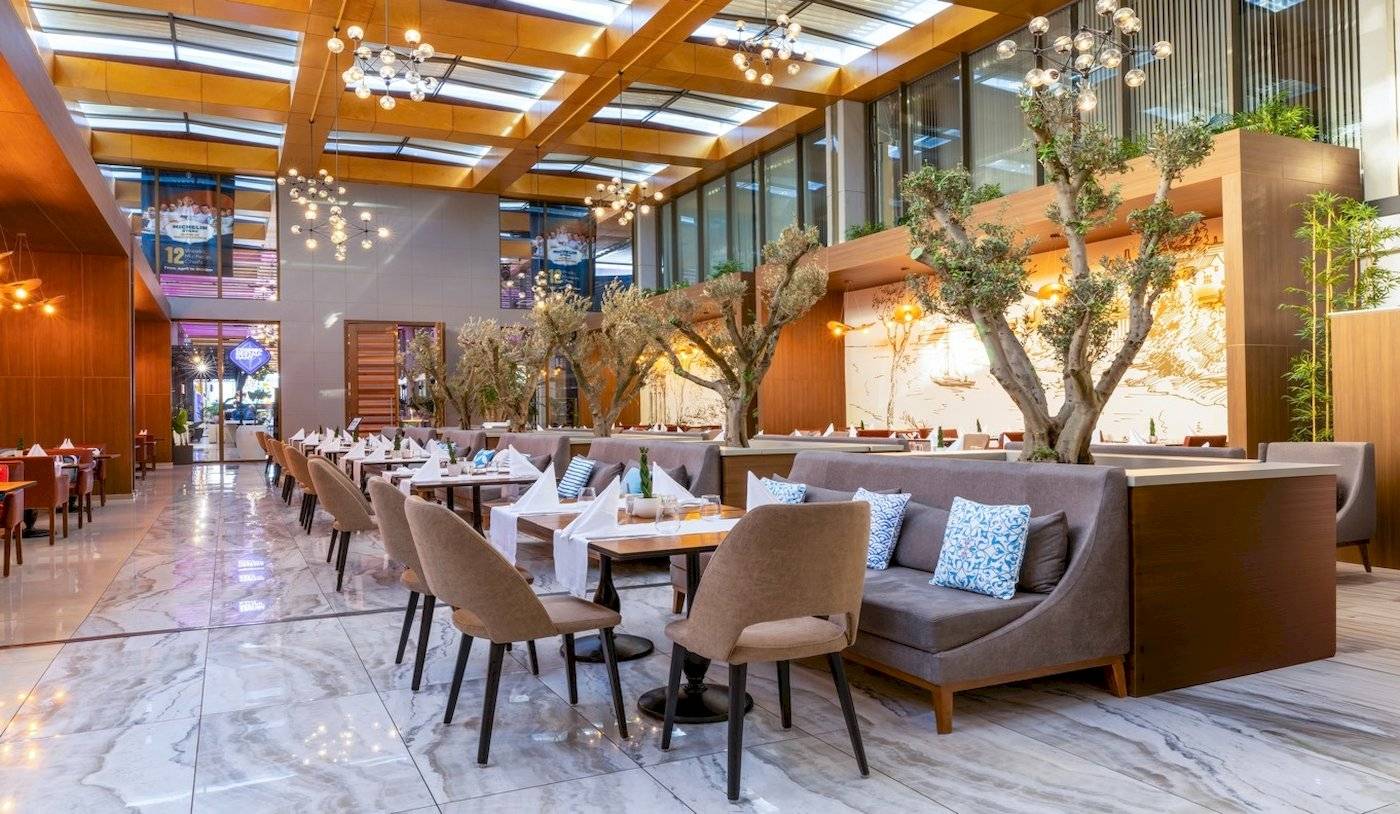 Interieur des Restaurants im Nirvana Cosmopolitan Hotel mit Sitzgelegenheiten und Esstischen.