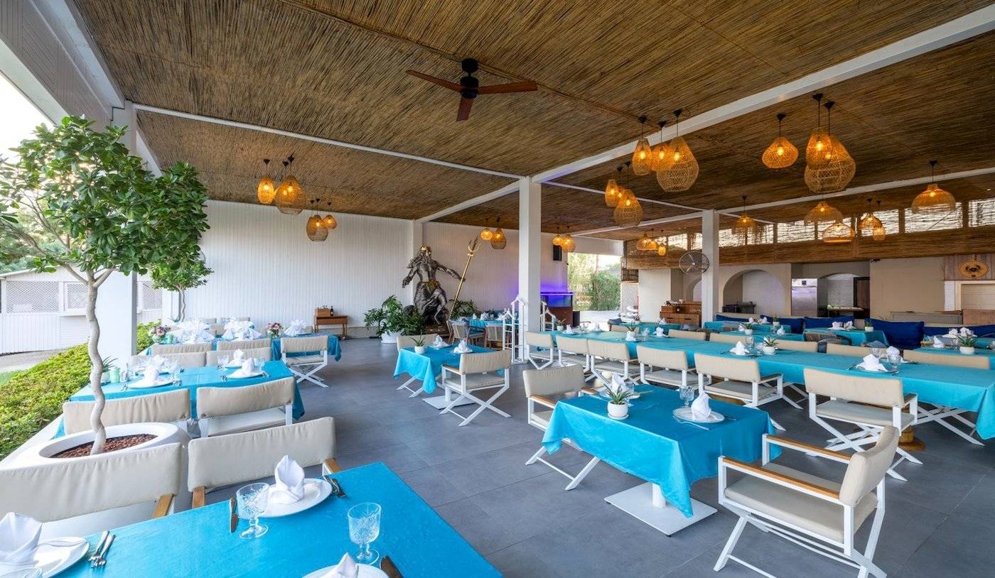 Innenbereich des Nirvana Cosmopolitan Hotels mit blauen Tischen und Stühlen, dekorierten Lampen und einer Statue.