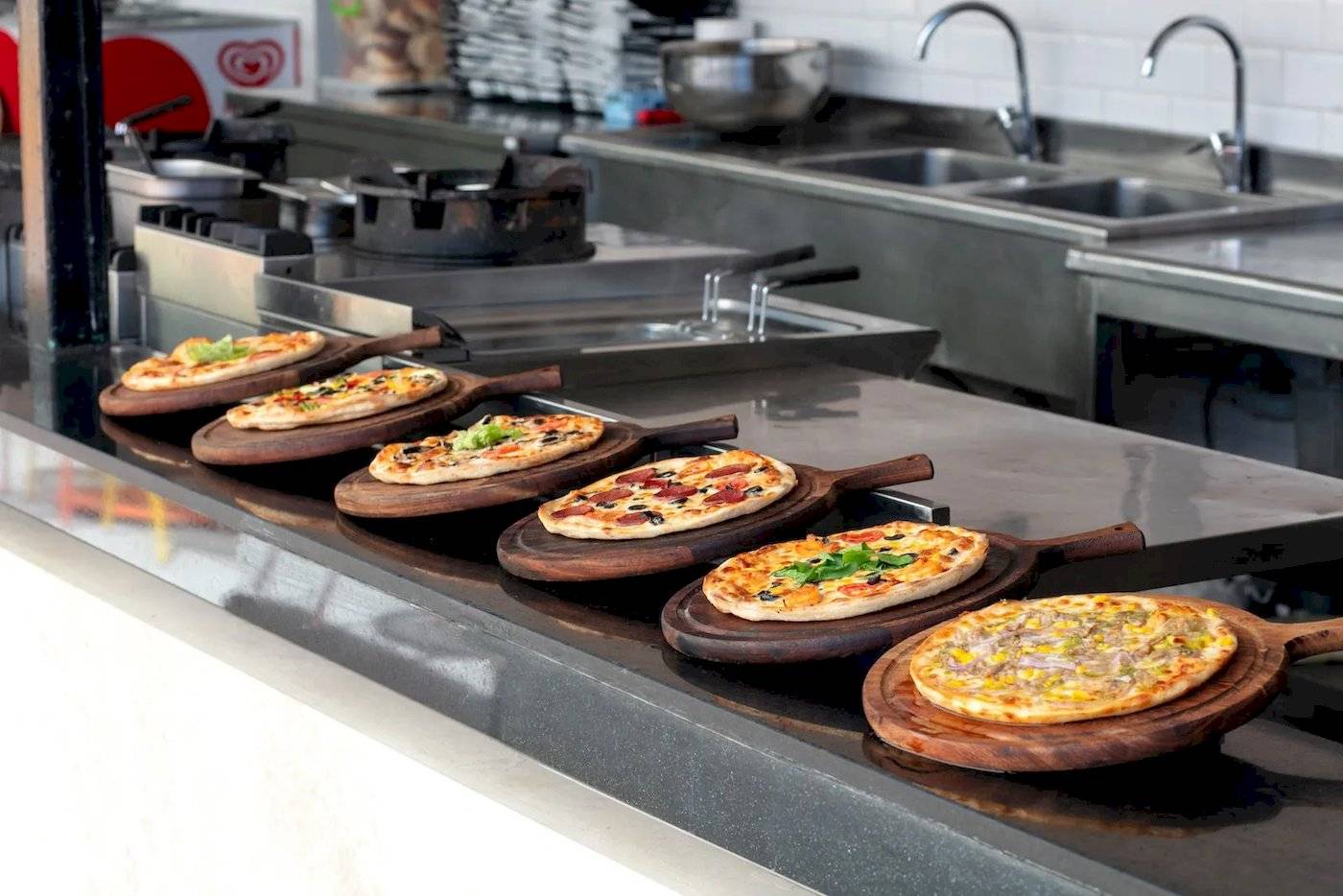 Mehrere Pizzen auf Holzplatten in der Küche des Megasaray Resort Side.