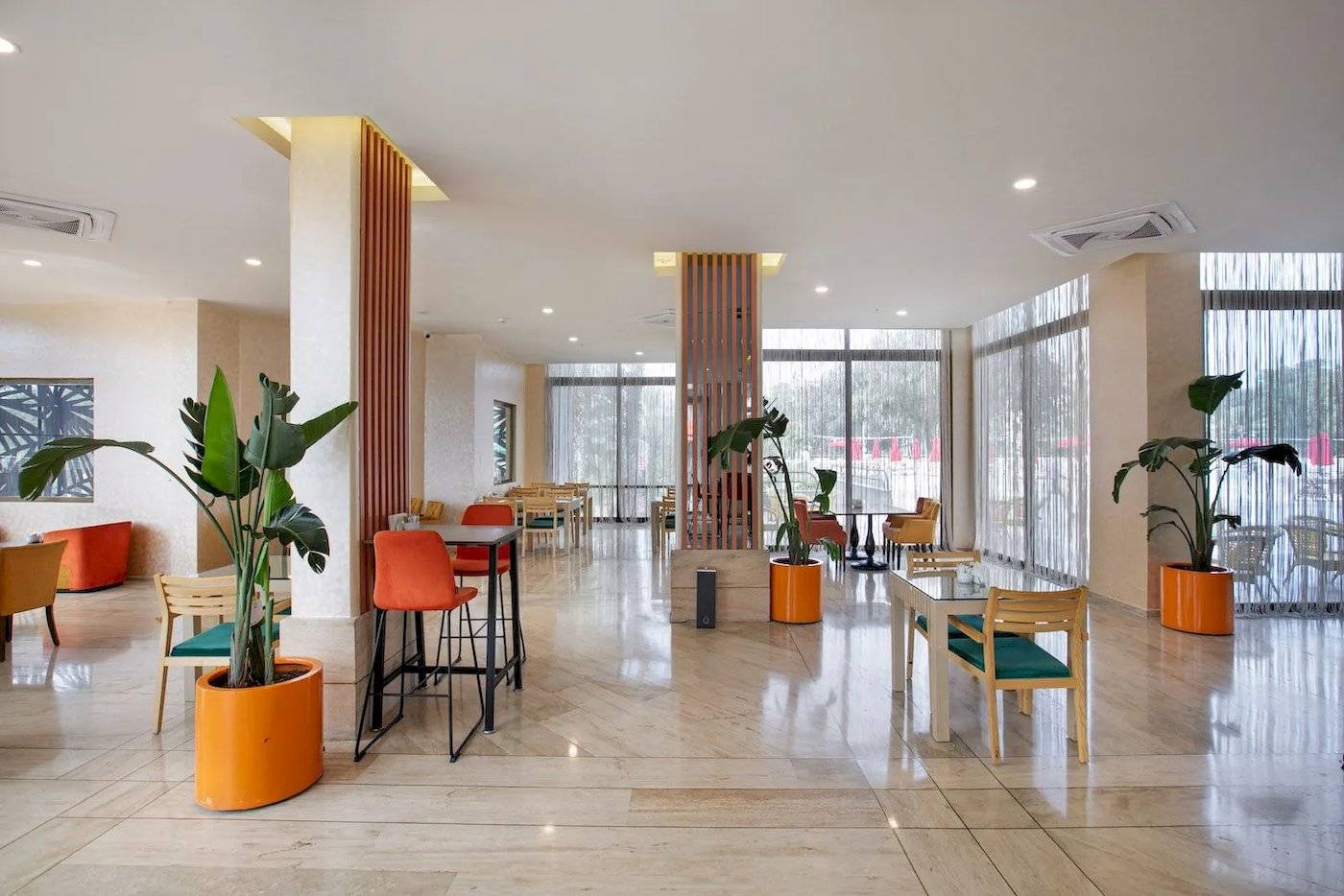 Innenbereich des Megasaray Resort Side mit Tischen, Stühlen und Pflanzen in orangefarbenen Töpfen.