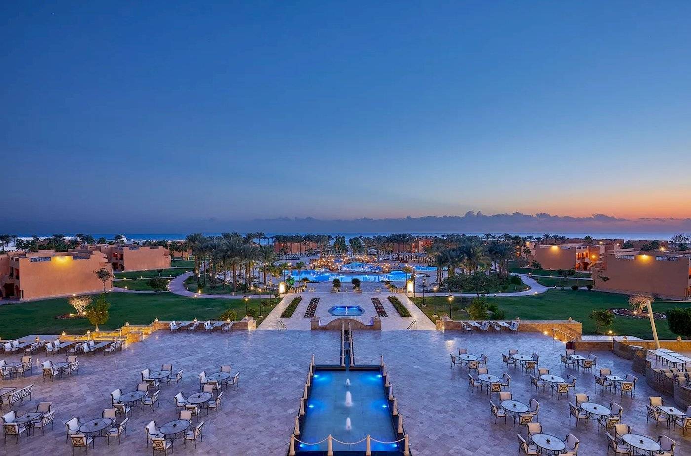 Luftaufnahme des Jaz Grand Marsa Hotels mit Swimmingpools und Außenbereichen bei Sonnenuntergang.