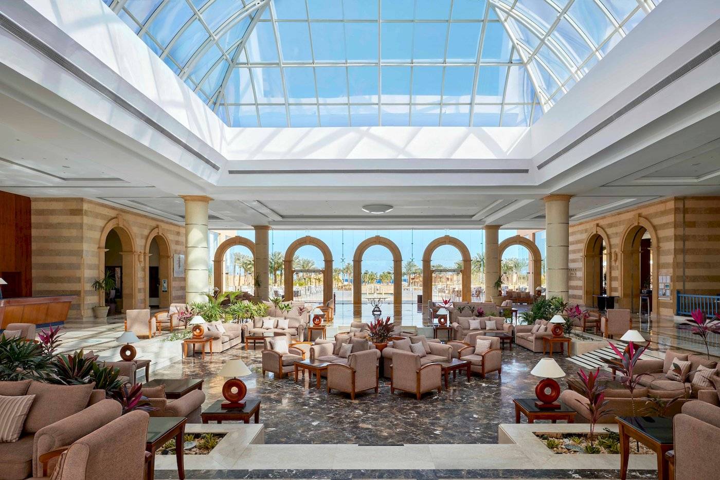 Lobby des Jaz Grand Marsa Hotels mit Glasdach und vielen Sitzgelegenheiten.