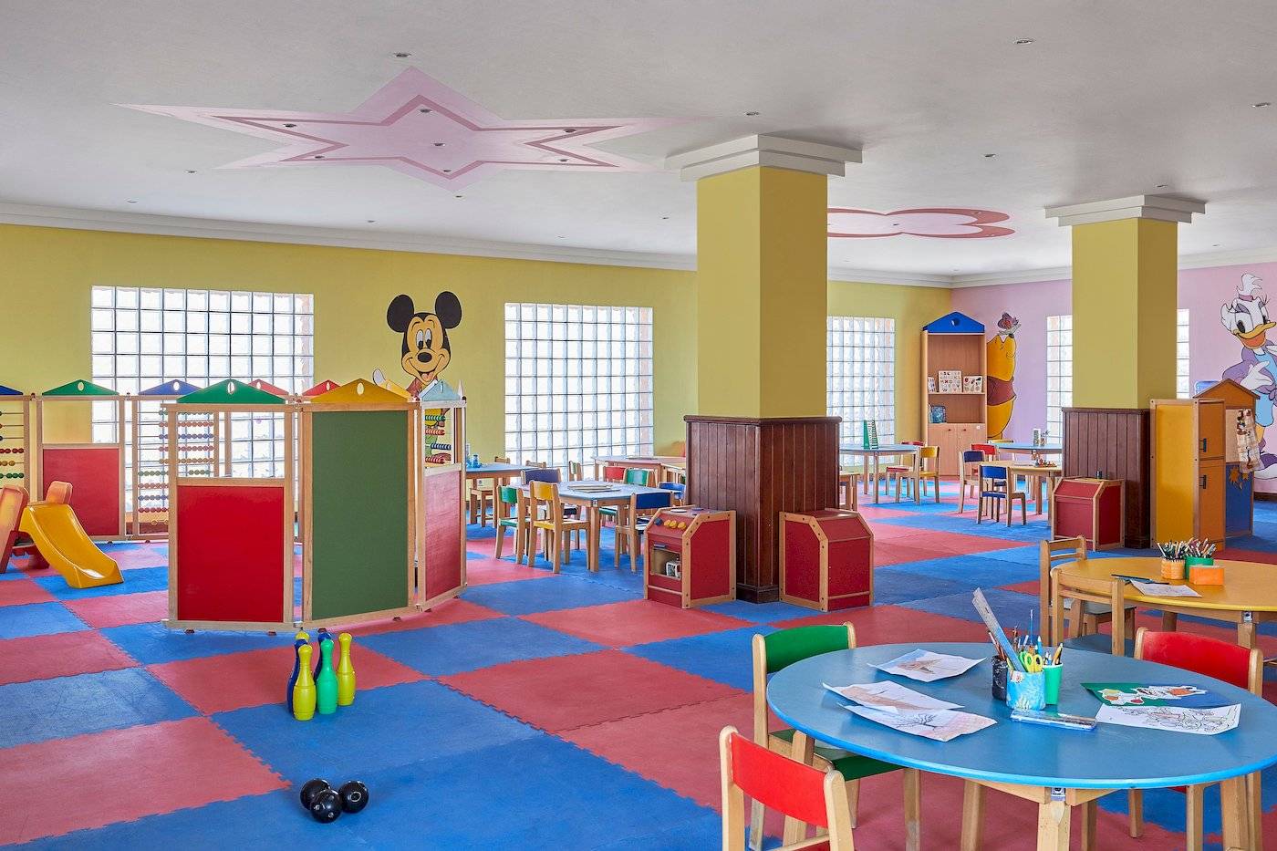 Spielzimmer im Jaz Grand Marsa Hotel mit bunten Teppichen, Disney-Zeichentrickfiguren und Spielzeug.