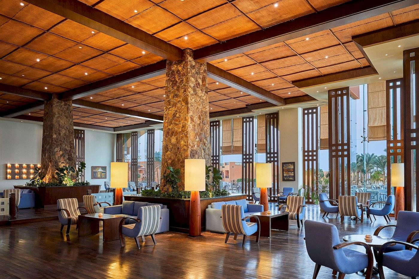 Innenansicht der Lobby im Jaz Grand Marsa Hotel mit blauen Stühlen und Holzböden.