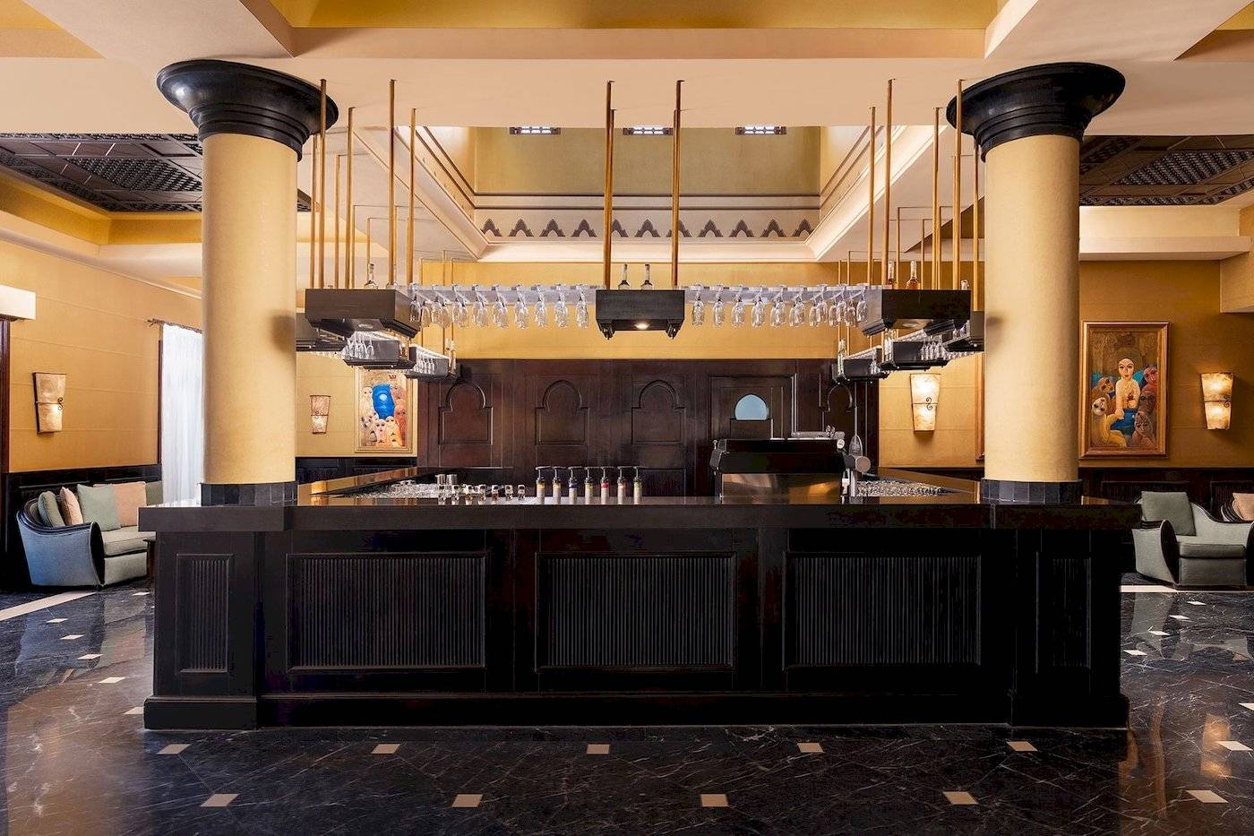 Innenbereich der Bar im Jaz Lamaya Resort Hotel mit schwarzen Theken und hohen Säulen.